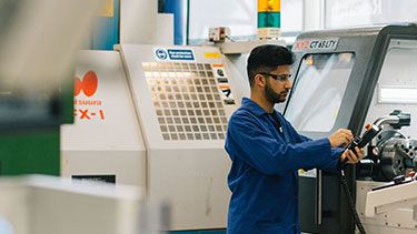 Engineering student in a lab coat working with machines