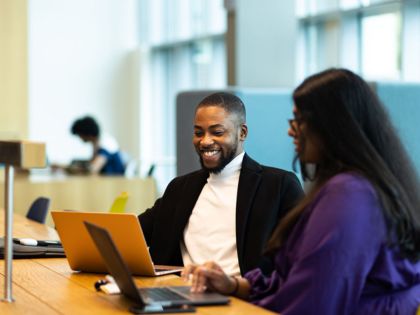 Student smiling at open laptop