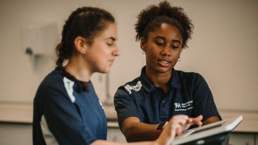 Sports students discussing information on a monitor