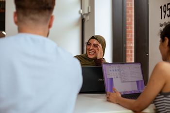 Students working on laptops and laughing
