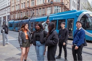 Group of students standing next to a tram
